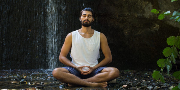 Hombre meditando, en posición de flor de loto en el bosque