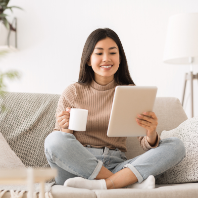 Mujer sonriente mirando su tablet con gesto alegre y relajado porque está alineandose a su proposito almico