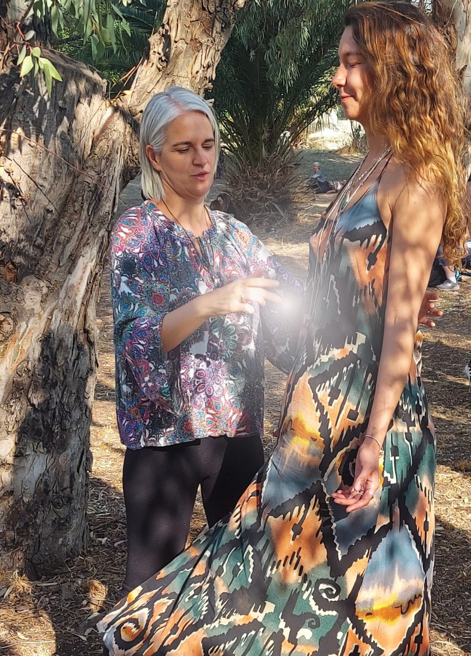 Miryam Ferris, energy healer in Phoenix, performing an energy healing session to a woman standing in the forest, with light entering through her body